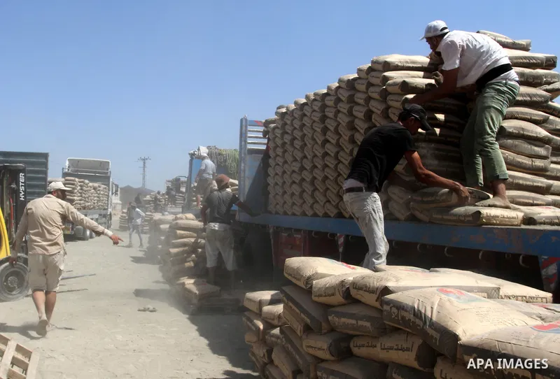 Palestinian workers offload a truck loaded with cement after it entered from Egypt through the Rafah border crossing in southern Gaza Strip, August 20, 2015. The authorities in Egypt have allowed 1,000 tons of cement and...