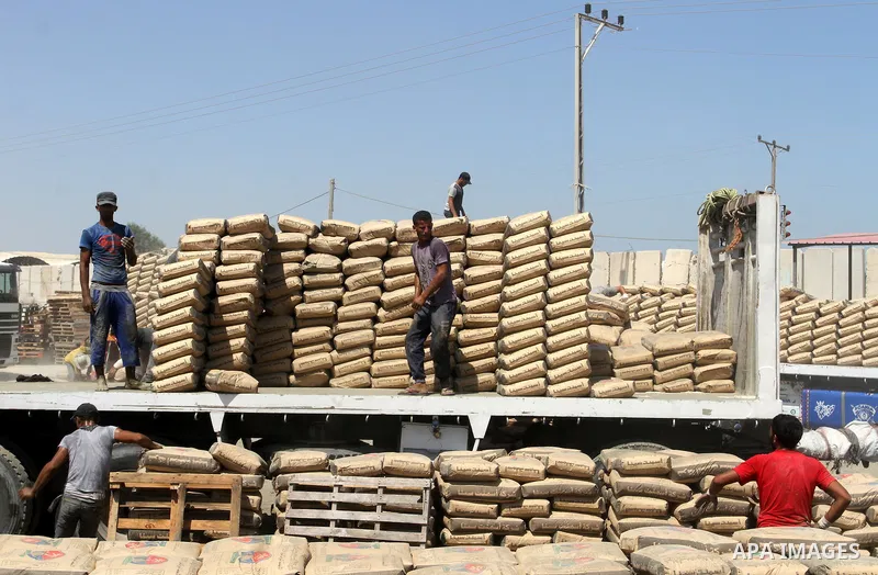 Palestinian workers offload a truck loaded with cement after it entered from Egypt through the Rafah border crossing in southern Gaza Strip, August 20, 2015. The authorities in Egypt have allowed 1,000 tons of cement and...