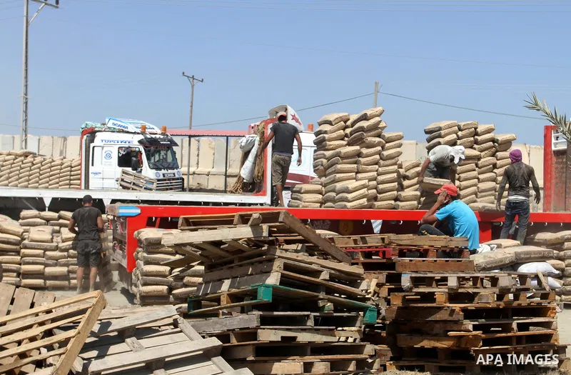 Palestinian workers offload a truck loaded with cement after it entered from Egypt through the Rafah border crossing in southern Gaza Strip, August 20, 2015. The authorities in Egypt have allowed 1,000 tons of cement and...