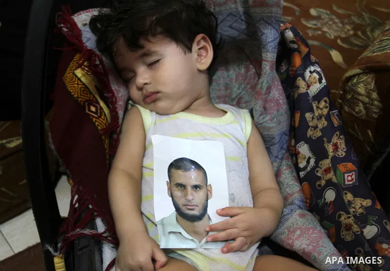The son of Yasser Zannoun, 27, holds his father's picture at their house in Rafah in the southern Gaza Strip, on August 20, 2015. Zannoun is one of four Palestinians were abducted in Egypt's Sinai Peninsula on Wednesday...