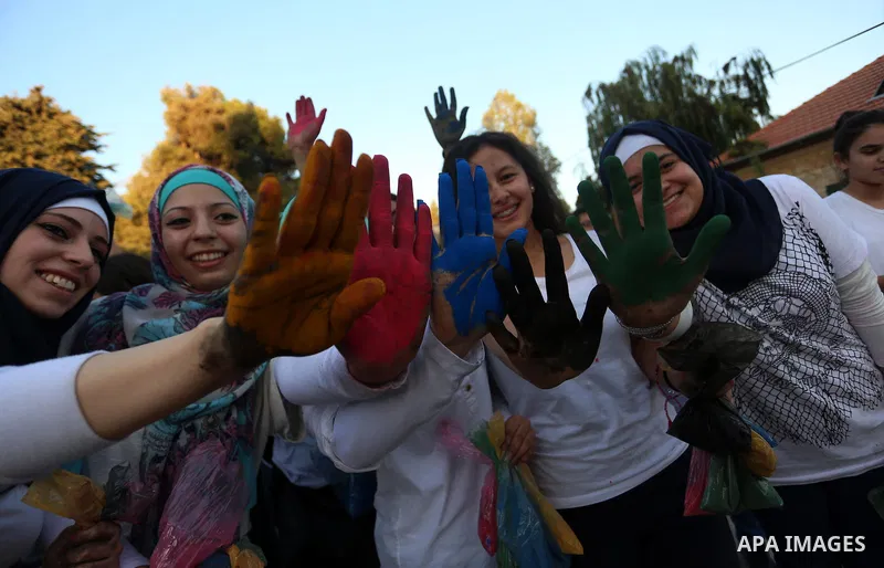 Palestinian girls show their colored hands during the festival of colour battle in the West Bank city of Ramallah on August 20, 2015. Photo by Shadi Hatem