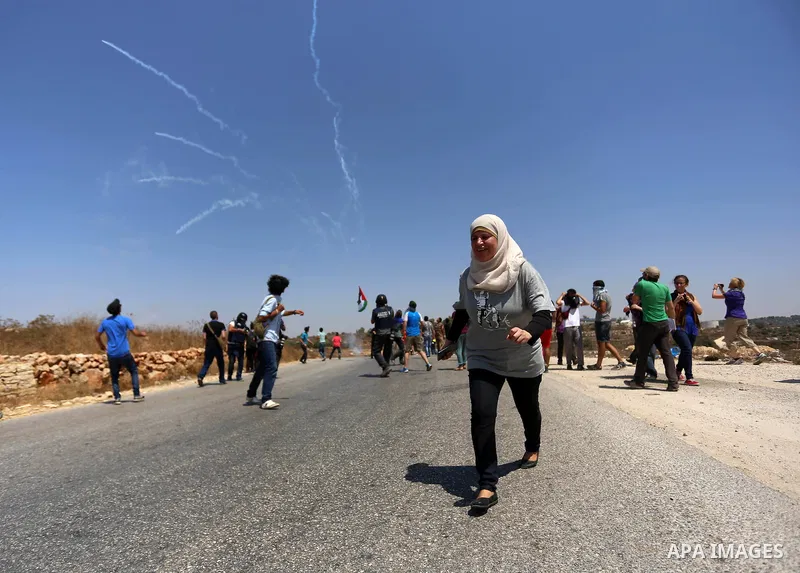 A Palestinian protester runs for cover from tear gas fired by Israeli security forces during clashes following a protest against Jewish settlements in the West Bank village of Nabi Saleh, near Ramallah August 21, 2015. P...