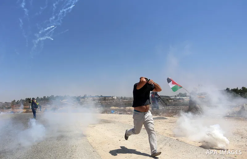 A Palestinian protester runs for cover from tear gas fired by Israeli security forces during clashes following a protest against Jewish settlements in the West Bank village of Nabi Saleh, near Ramallah August 21, 2015. P...