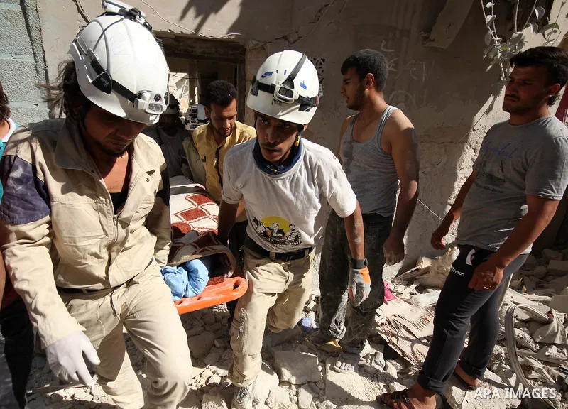 Syrian rescue workers carry a body of a man following a reported barrel-bomb attack by Syrian government forces, in the Tariq al-Bab neighbourhood in the northern city of Aleppo, on August 21, 2015. Photo by Ameer al-Hal...