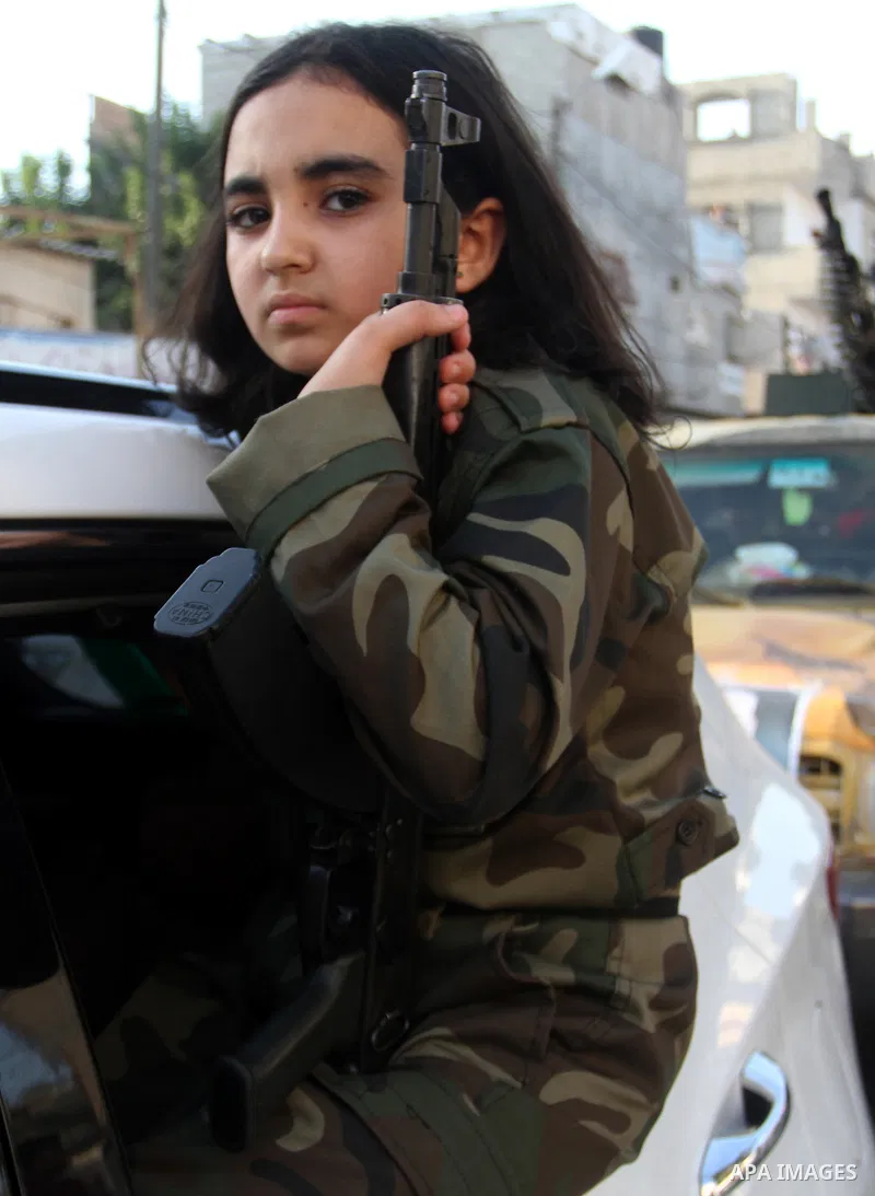 A Palestinian girl wears the al-Qassam Brigades costume during a military parade marking the first anniversary of the killing of Hamas's military commanders Mohammed Abu Shamala and Raed al-Attar, in Rafah in the souther...
