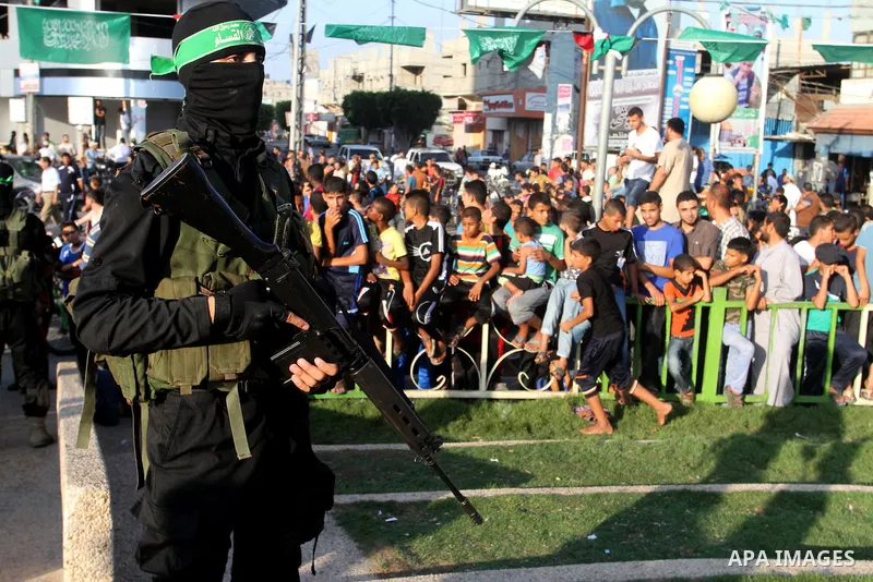 Palestinian children watch a military parade of members of the al-Qassam Brigades, the armed wing of the Hamas movement, to mark the first anniversary of the killing of Hamas's military commanders Mohammed Abu Shamala an...