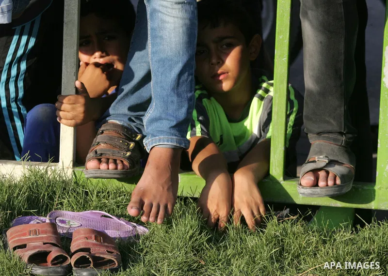 Palestinian children watch a military parade of members of the al-Qassam Brigades, the armed wing of the Hamas movement, to mark the first anniversary of the killing of Hamas's military commanders Mohammed Abu Shamala an...