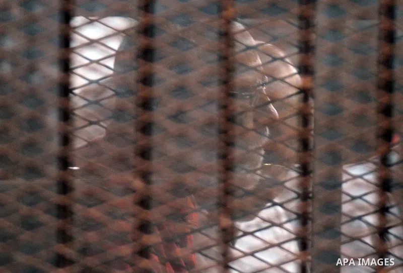 Egyptian Muslim Brotherhood leader Mohamed Badie sits behind the defendant's cage as he attends his trial, in a courtroom in Torah prison, southern Cairo, Egypt, Saturday, Aug. 22, 2015. The court sentenced Muslim Brothe...