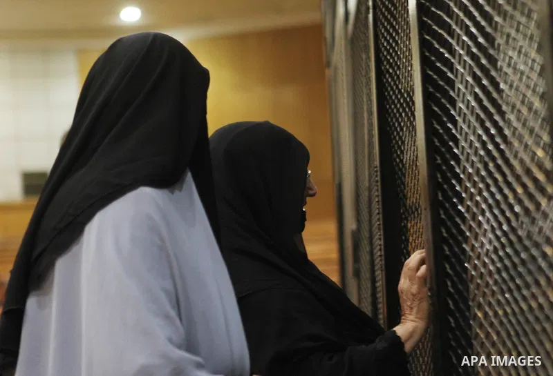 Relatives speak with Egyptian Muslim Brotherhood defendants as they stand behind the bars during their trial, along with ousted Islamist president Mohamed Morsi (unseen) in Cairo on August 22, 2015. The Cairo court resum...
