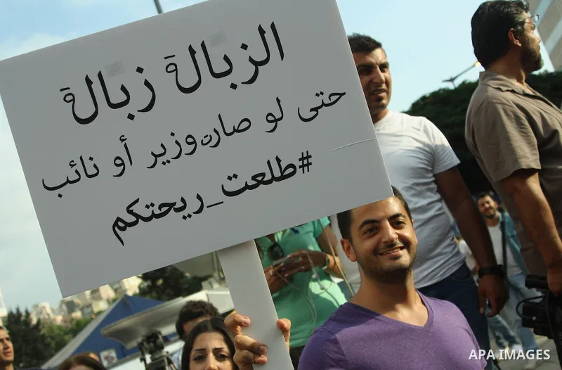 Lebanese protesters hold banners and national flags during a demonstration, against the ongoing trash crisis in the capital Beirut on August 22, 2015. Thousands of protesters, including children, gathered to protest the...