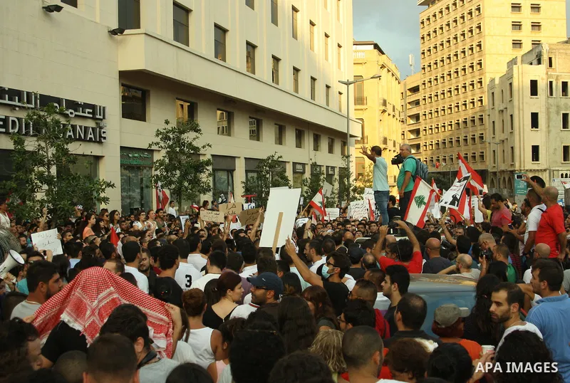 Lebanese protesters hold banners and national flags during a demonstration, against the ongoing trash crisis in the capital Beirut on August 22, 2015. Thousands of protesters, including children, gathered to protest the...