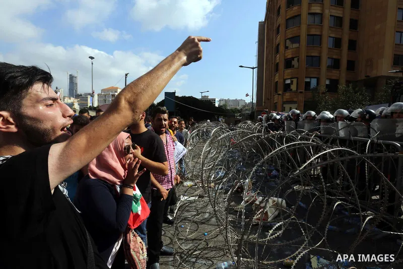 Lebanese protesters shot slogans in front of a barbed wire fence during a demonstration, organized by "You Stink" campaign, to protest against the ongoing country's trash crisis in the capital Beirut on August 23, 2015....