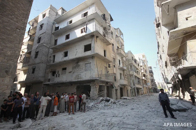 Syrian men walk on the rubble of buildings following a reported bomb barrel attack by Syrian government forces at Salah AL-Dien neighborhood in the northern Syrian city of Aleppo, August 25, 2015. Photo by Ameer al-Halbi