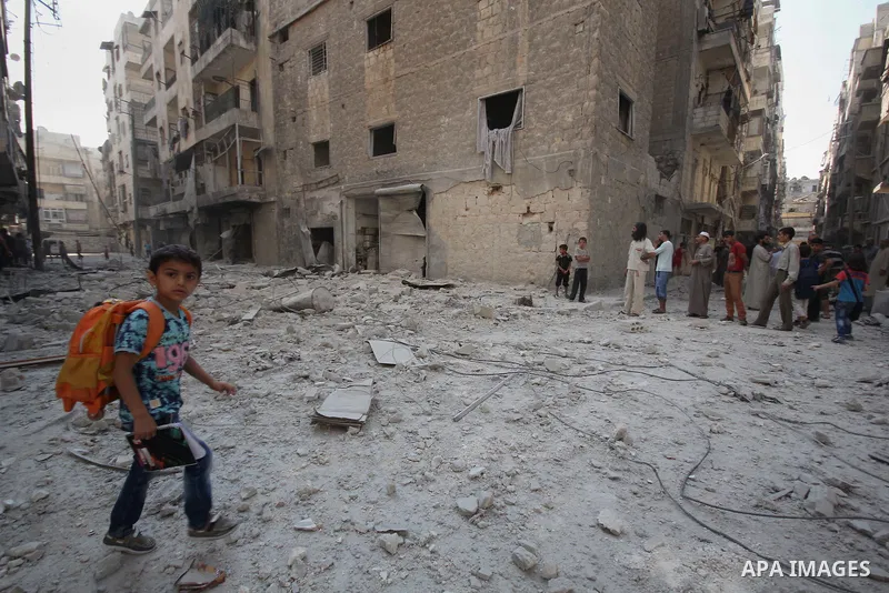 Syrian men walk on the rubble of buildings following a reported bomb barrel attack by Syrian government forces at Salah AL-Dien neighborhood in the northern Syrian city of Aleppo, August 25, 2015. Photo by Ameer al-Halbi