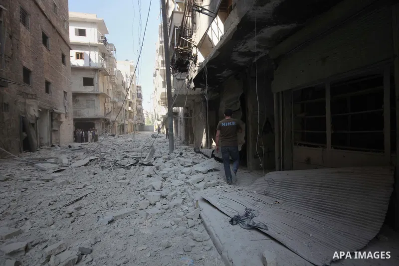 Syrian men walk on the rubble of buildings following a reported bomb barrel attack by Syrian government forces at Salah AL-Dien neighborhood in the northern Syrian city of Aleppo, August 25, 2015. Photo by Ameer al-Halbi