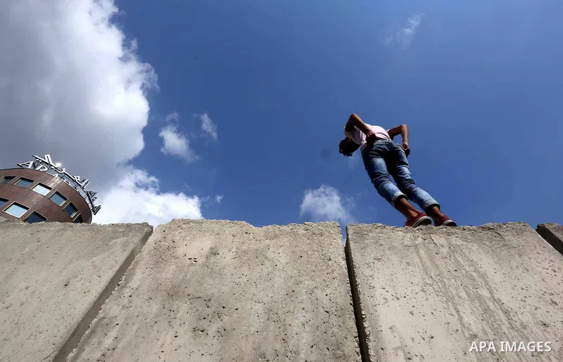 A Lebanese man stands on a concrete blast wall, spread with graffiti depicting various political groups and bearing messages against police brutality, before its dismantlement, in front of the seat of the government in c...
