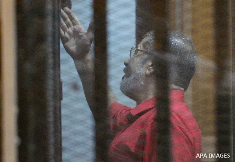 Ousted Egyptian president Mohammed Morsi speaks to the judge as he stands behind bars during his trail in a court in Cairo on August 30, 2015. Cairo criminal court resumes today the trial of deposed president Mohamed Mor...
