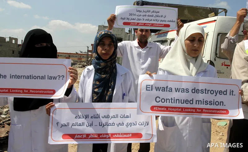 Palestinian Medical workers hold placards during a protest demanding reconstruction of El-Wafa hospital, which witnesses said was destroyed during a seven-week Israeli offensive, in the east of Gaza City on Sep. 01, 2015...