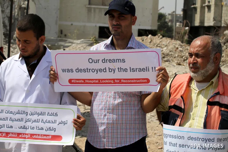Palestinian Medical workers hold placards during a protest demanding reconstruction of El-Wafa hospital, which witnesses said was destroyed during a seven-week Israeli offensive, in the east of Gaza City on Sep. 01, 2015...