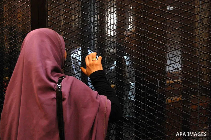 A Relative speaks with Egyptian Muslim Brotherhood defendants as he stands behind the bars during his trial, along with ousted Islamist president Mohamed Morsi (unseen), in a court in Cairo on Sep. 01, 2015. Cairo crimin...