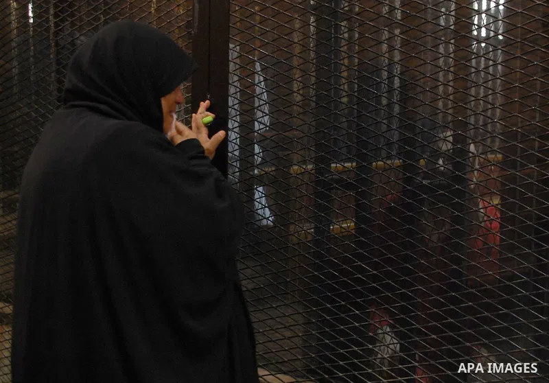 A Relative speaks with Egyptian Muslim Brotherhood defendants as he stands behind the bars during his trial, along with ousted Islamist president Mohamed Morsi (unseen), in a court in Cairo on Sep. 01, 2015. Cairo crimin...