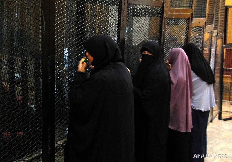 Relatives speak with Egyptian Muslim Brotherhood defendants as they stands behind the bars during his trial, along with ousted Islamist president Mohamed Morsi (unseen), in a court in Cairo on Sep. 01, 2015. Cairo crimin...