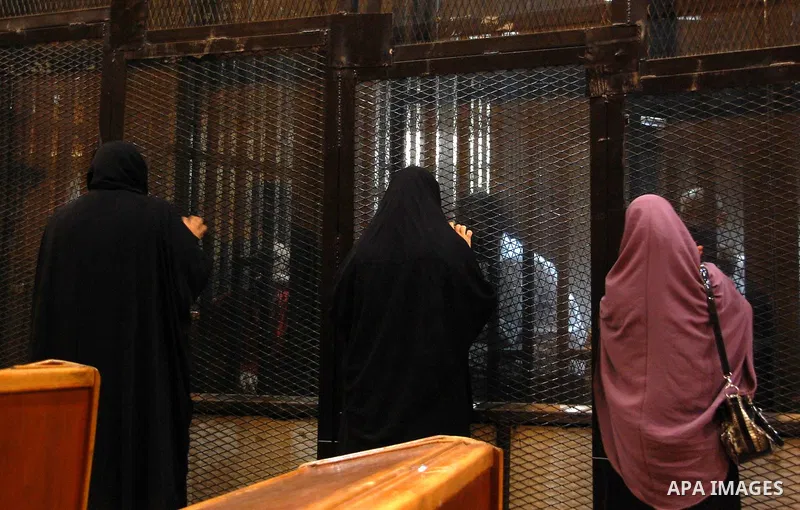 Relatives speak with Egyptian Muslim Brotherhood defendants as they stands behind the bars during his trial, along with ousted Islamist president Mohamed Morsi (unseen), in a court in Cairo on Sep. 01, 2015. Cairo crimin...