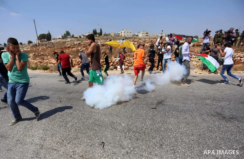 Palestinian protesters run for cover from a tear gas fired by Israeli border policemen during a protest against Jewish settlements in the West Bank village of Nabi Saleh, near Ramallah September 4, 2015. Photo by Shadi H...