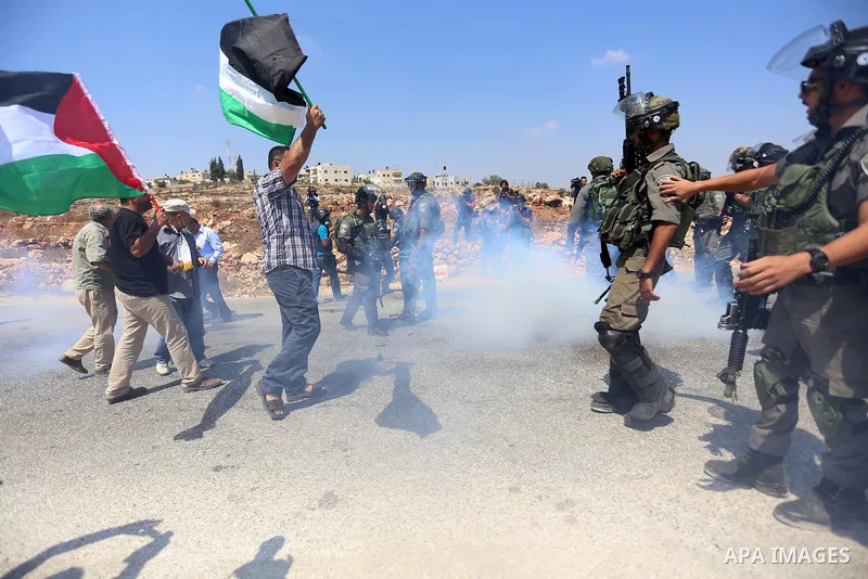 A Palestinian protester waves a Palestinian flag as he stands in front of Israeli border policemen during a protest against Jewish settlements in the West Bank village of Nabi Saleh, near Ramallah September 4, 2015. Phot...