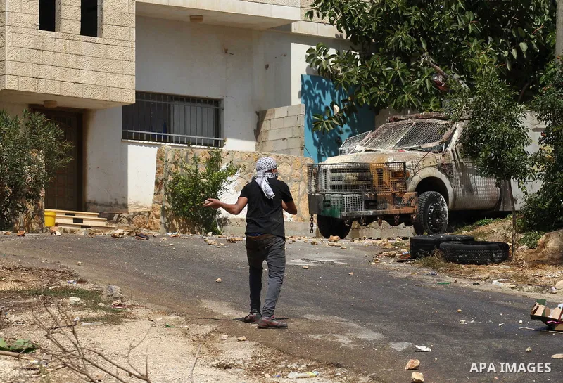 A Palestinian protester throws stones towards Israeli security forces during clashes following a demonstration against the expropriation of Palestinian land by Israel, in the village of Kfar Qaddum, near Nablus in the oc...