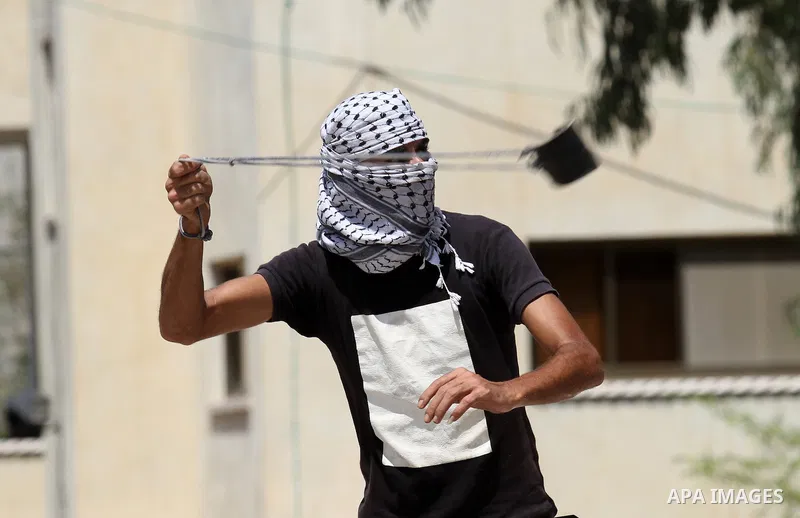 A Palestinian protester uses a slingshot to throw stones towards Israeli security forces during clashes following a demonstration against the expropriation of Palestinian land by Israel, in the village of Kfar Qaddum, ne...