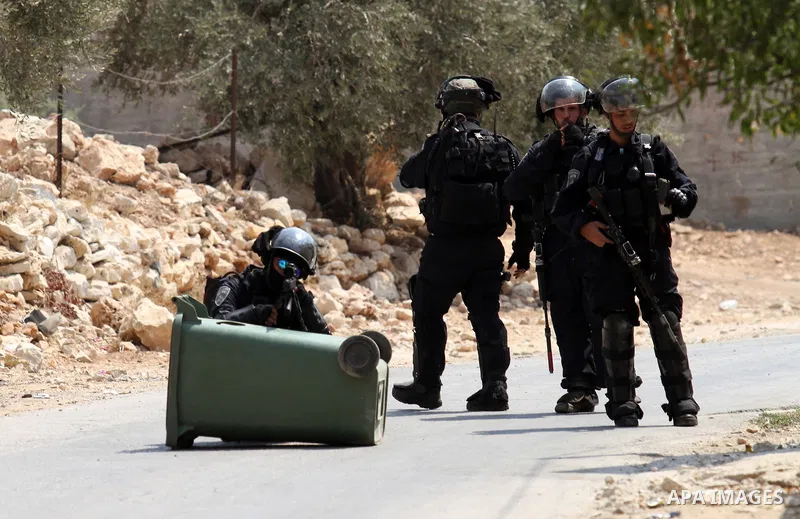 A member of Israeli security forces aims his weapon towars Palestinian protesters during clashes following a demonstration against the expropriation of Palestinian land by Israel, in the village of Kfar Qaddum, near Nabl...