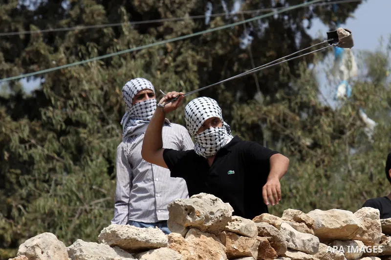 A Palestinian protester uses a slingshot to throw stones towards Israeli security forces during clashes following a demonstration against the expropriation of Palestinian land by Israel, in the village of Kfar Qaddum, ne...