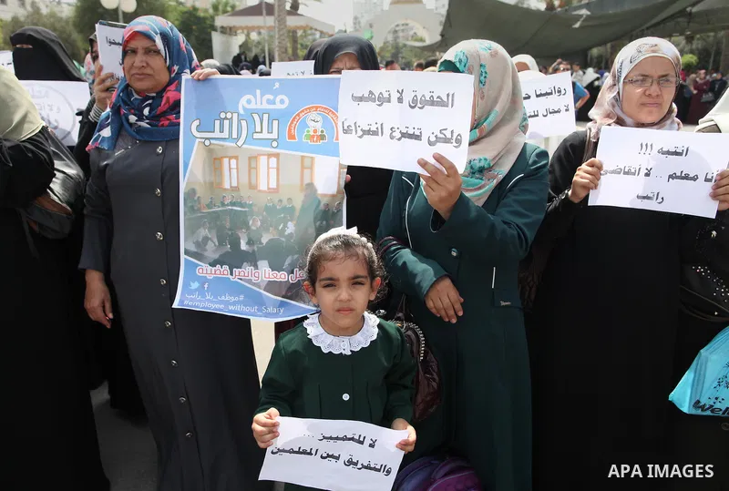 Palestinian teachers hold banners during a protest to demand their salaries and their rights, in Gaza City, on September 7, 2015. Photo by Ashraf Amra