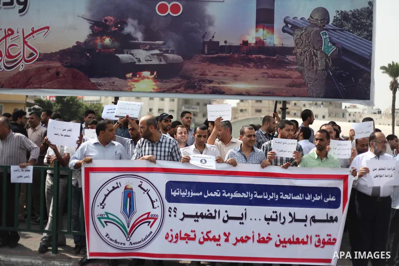 Palestinian teachers hold banners during a protest to demand their salaries and their rights, in Gaza City, on September 7, 2015. Photo by Ashraf Amra
