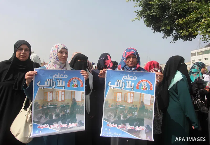 Palestinian teachers hold banners during a protest to demand their salaries and their rights, in Gaza City, on September 7, 2015. Photo by Ashraf Amra