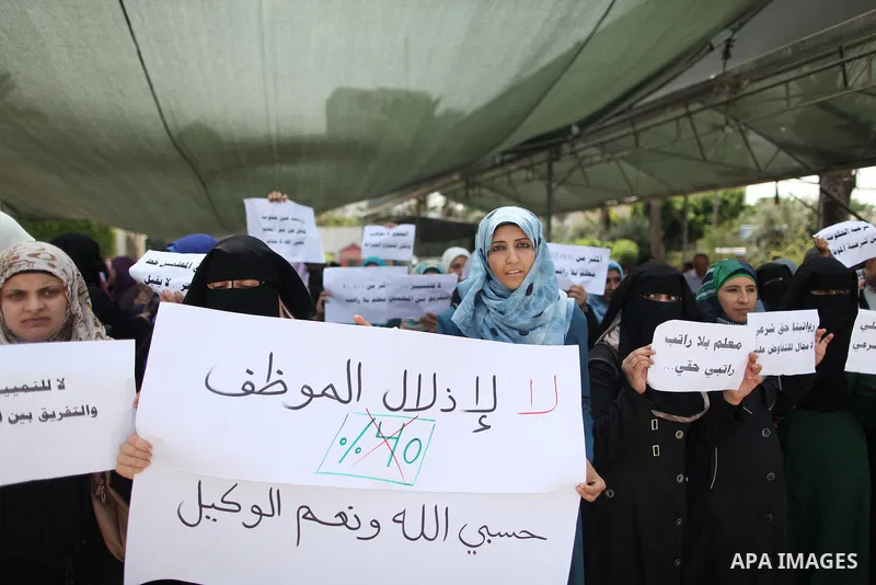 Palestinian teachers hold banners during a protest to demand their salaries and their rights, in Gaza City, on September 7, 2015. Photo by Ashraf Amra