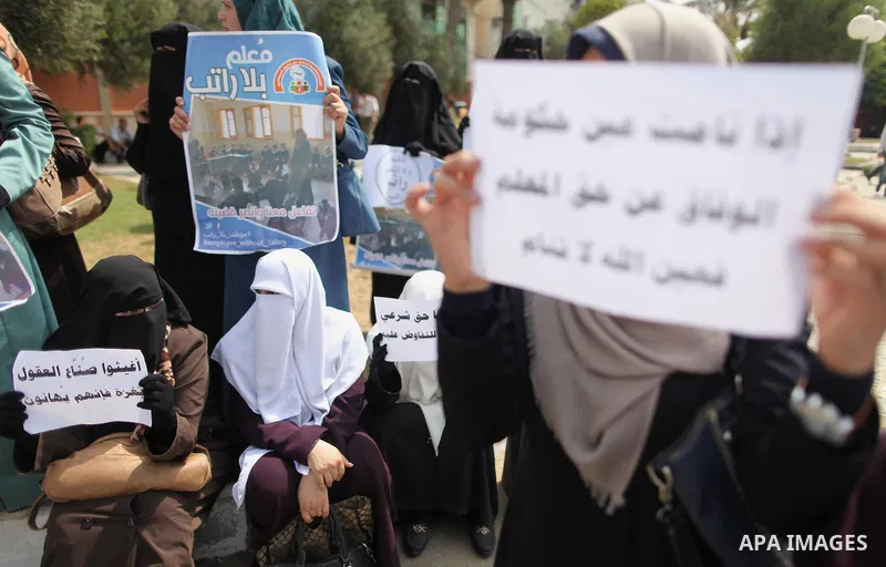 Palestinian teachers hold banners during a protest to demand their salaries and their rights, in Gaza City, on September 7, 2015. Photo by Ashraf Amra