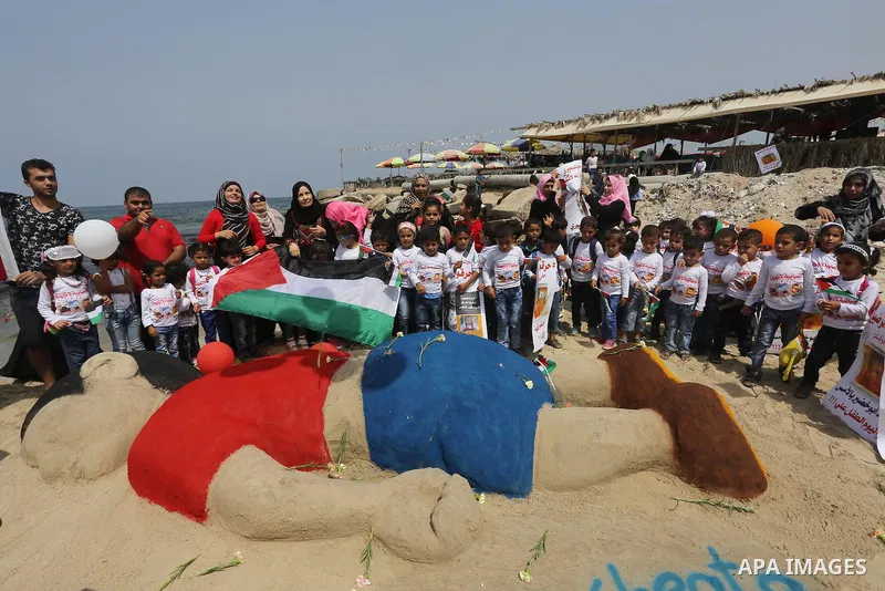 Palestinian children hold flowers and flags to remember Aylan Kurdi, a Syrian three-year-old boy whose drowning off a Turkish beach, during a protest at the beach of Gaza city, on Sep. 07, 2015. Photo by Mohammed Asad