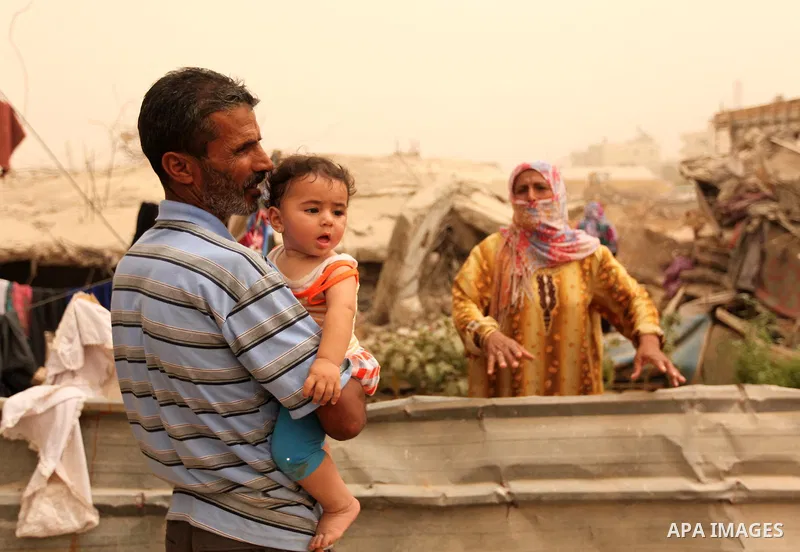 Palestinians stand outside their house that witnesses said were destroyed by Israeli during a 50-day shelling in 2014 summer, during a sandstorm in Khan Younis in the southern Gaza Strip, September 9, 2015. A heavy sands...
