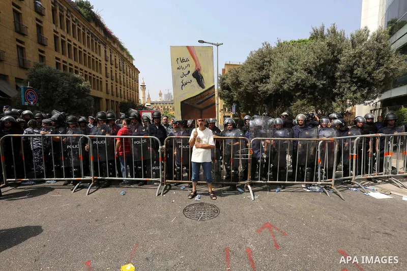 A Lebanese activist from 'You Stink' campaign stands in front of riot police during a protest against today s session of a dialogue of top political figures, accused by the group of failing to resolve a crisis over rubbi...