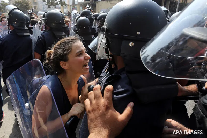 A Lebanese activist from 'You Stink' campaign shouts slogans in front of riot police during a protest against today s session of a dialogue of top political figures, accused by the group of failing to resolve a crisis ov...