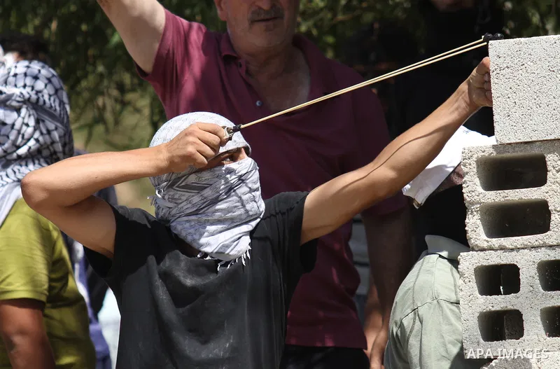 A Palestinian protester uses a sling shot to hurl a stone towards Israeli security forces during clashes following a demonstration in defence of the Al-Aqsa mosque, Islam s third holiest site, located in Jerusalem's old...