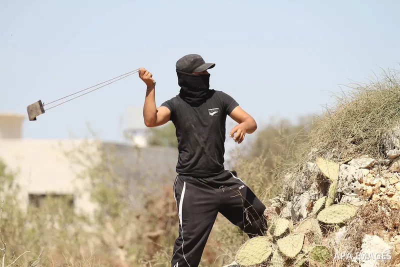 A Palestinian protester uses a sling shot to hurl a stone towards Israeli security forces during clashes following a demonstration in defence of the Al-Aqsa mosque, Islam s third holiest site, located in Jerusalem's old...