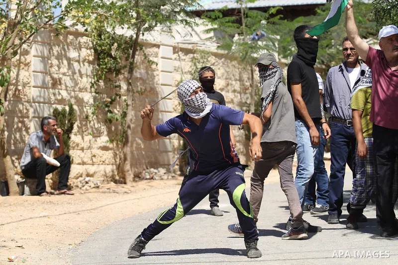 A Palestinian protester uses a sling shot to hurl a stone towards Israeli security forces during clashes following a demonstration in defence of the Al-Aqsa mosque, Islam s third holiest site, located in Jerusalem's old...