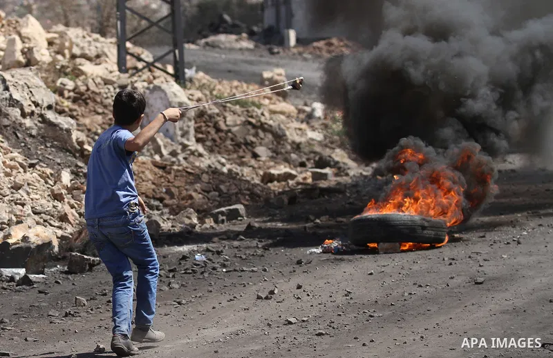 A Palestinian protester uses a sling shot to hurl a stone towards Israeli security forces during clashes following a demonstration in defence of the Al-Aqsa mosque, Islam s third holiest site, located in Jerusalem's old...