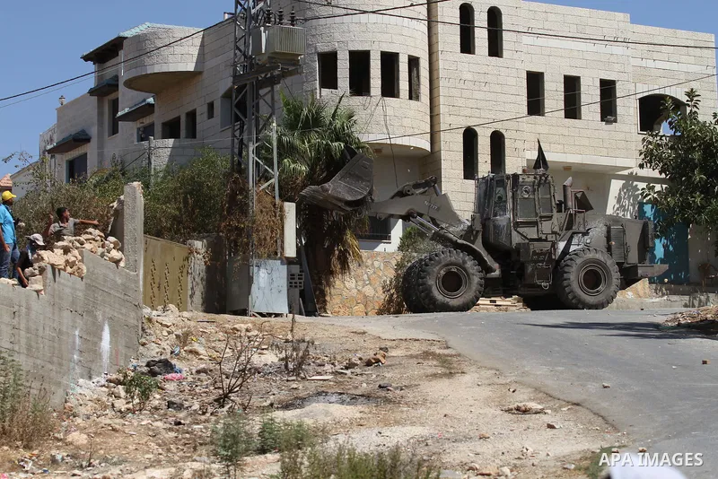Palestinian protesters throw stones towards an Israeli military bulldozer during clashes following a demonstration in defence of the Al-Aqsa mosque, Islam s third holiest site, located in Jerusalem's old city, after the...