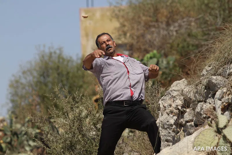 A Palestinian protester throws a stone towards Israeli security forces during clashes following a demonstration in defence of the Al-Aqsa mosque, Islam s third holiest site, located in Jerusalem's old city, after the wee...