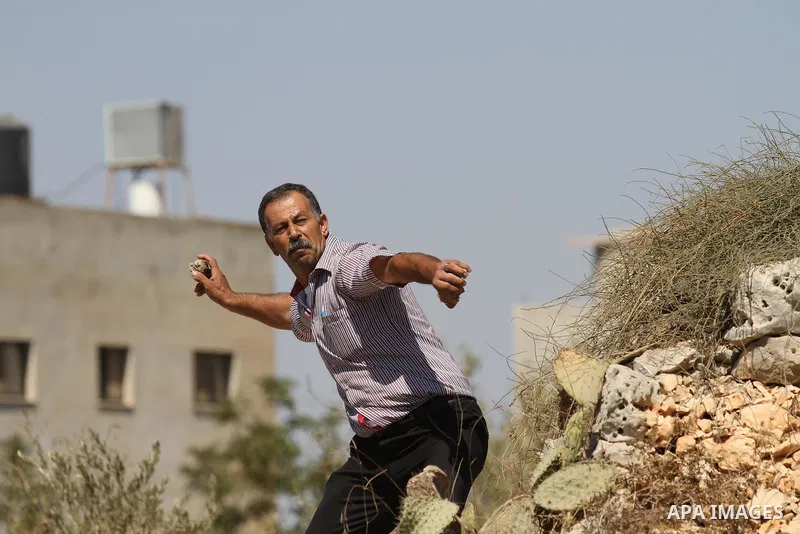 A Palestinian protester throws a stone towards Israeli security forces during clashes following a demonstration in defence of the Al-Aqsa mosque, Islam s third holiest site, located in Jerusalem's old city, after the wee...