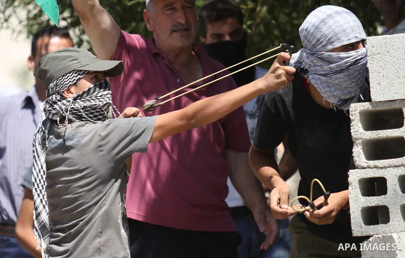 A Palestinian protester uses a sling shot to hurl a stone towards Israeli security forces during clashes following a demonstration in defence of the Al-Aqsa mosque, Islam s third holiest site, located in Jerusalem's old...